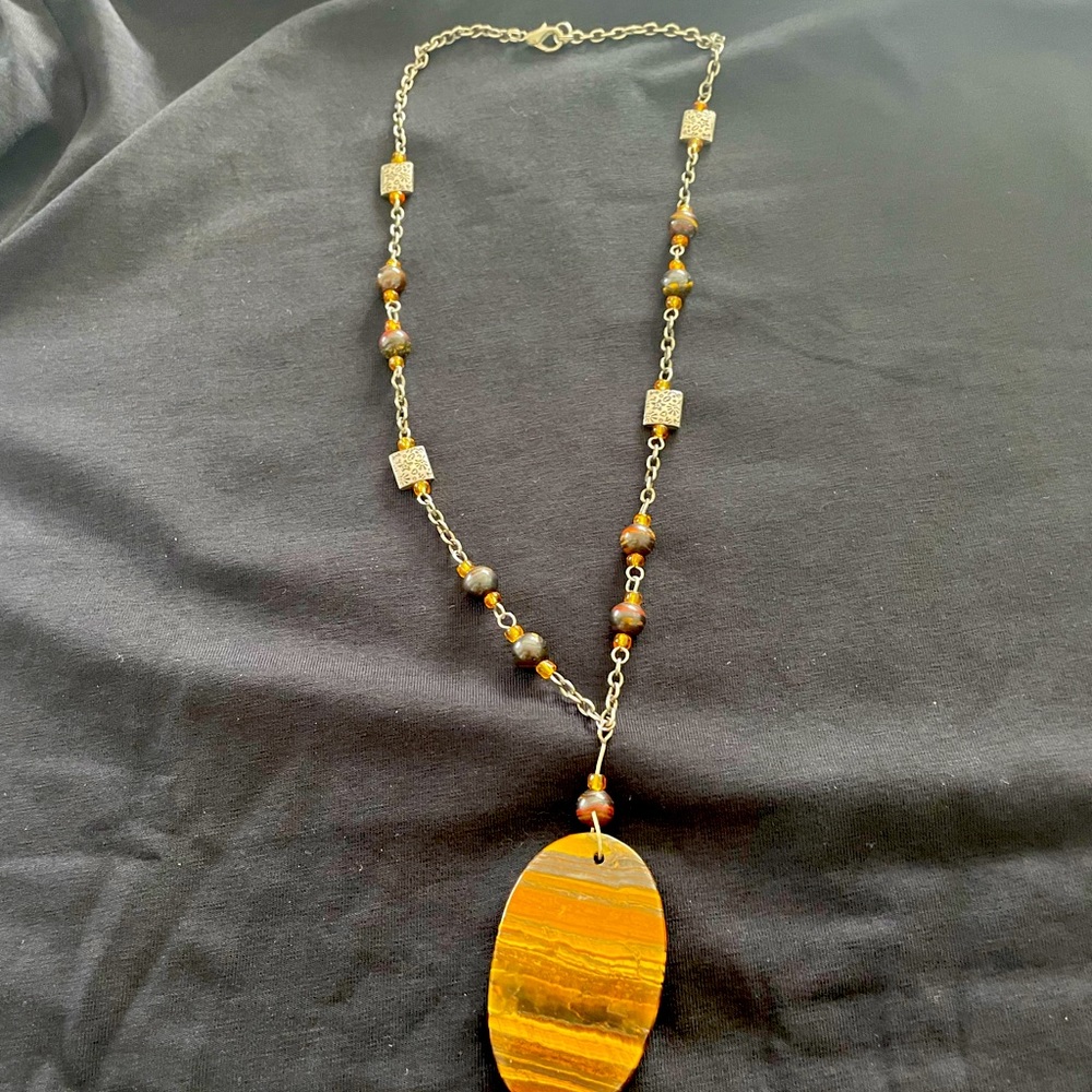 Lovely earth tone pendant on a beaded grey chain.